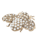 Gold brooch with pearl embellishments on a white background