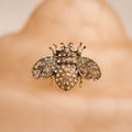 Gold bee-shaped brooch with gemstones on a blurred background