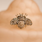 Gold bee-shaped brooch with gemstones on a blurred background