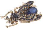 Gold insect-shaped brooch with blue gemstones on a white background