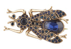 Gold frog brooch with blue gemstones on a white background