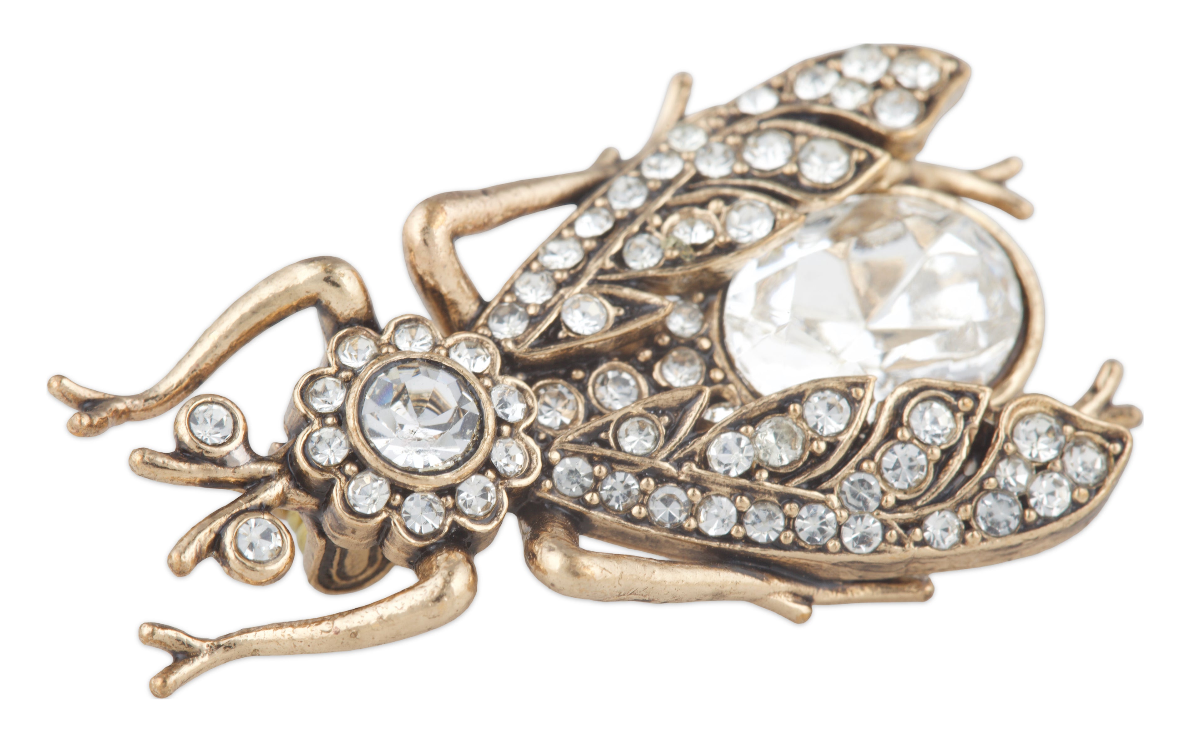 Decorative brooch shaped like a beetle with crystal embellishments on a white background