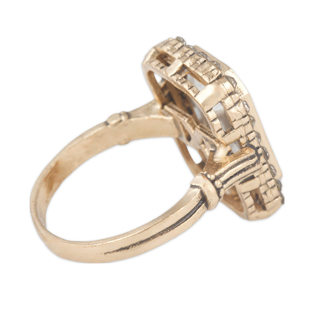 Gold ring with architectural design on a white background