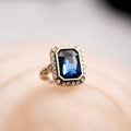 Gold ring with a blue gemstone on a blurred background