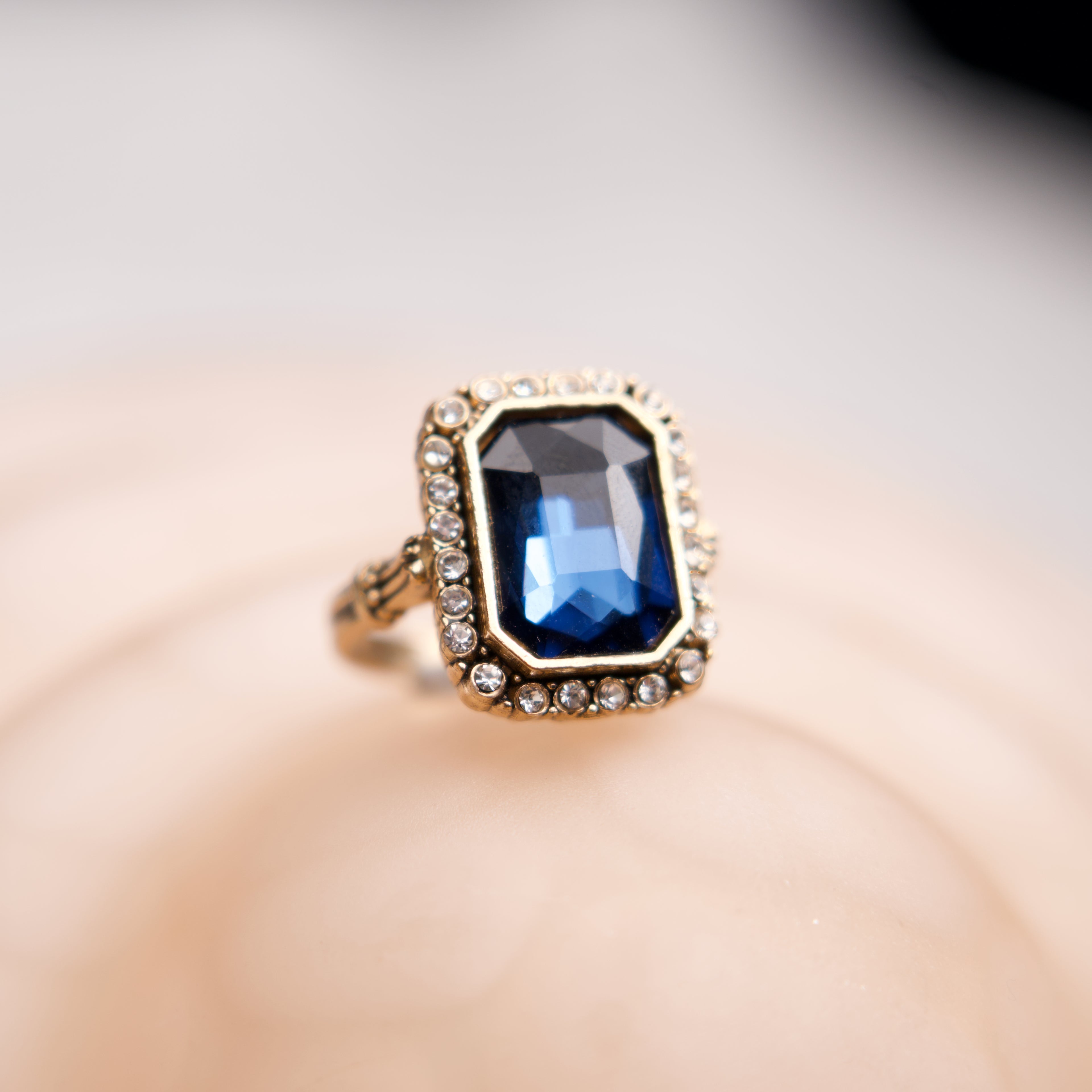 Gold ring with a blue gemstone on a blurred background