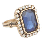Ring with blue gemstone and gold accents on a white background