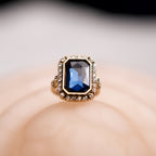 Gold ring with a blue gemstone on a soft beige background