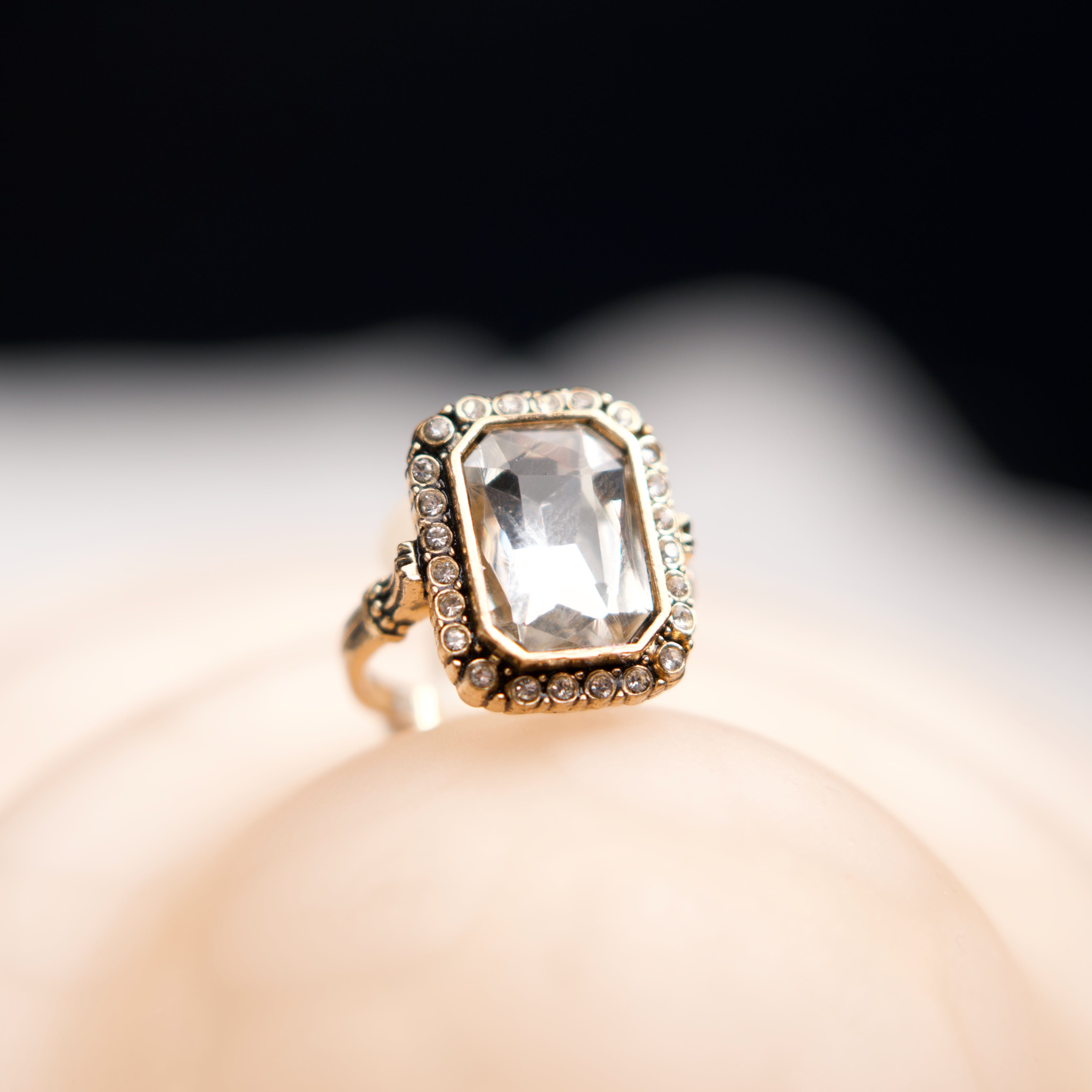 Gold ring with a clear gemstone on a blurred background
