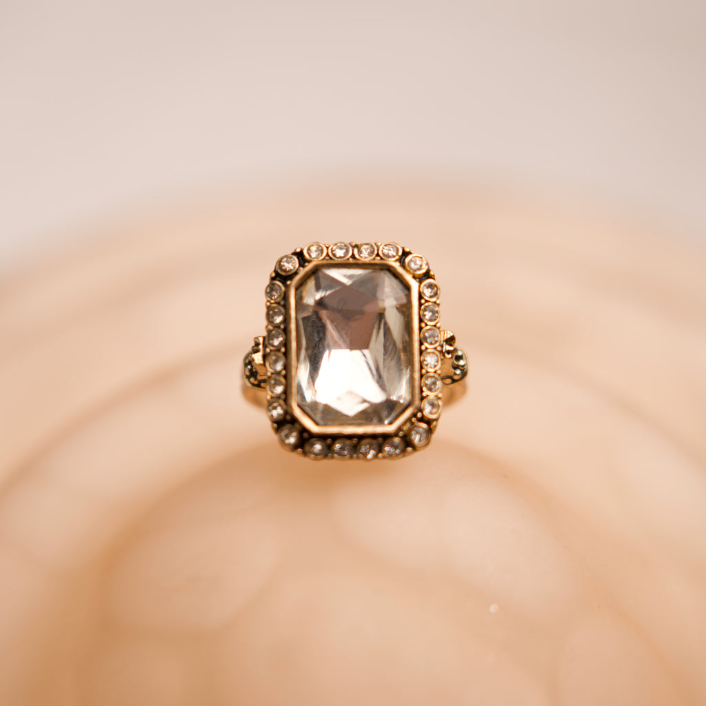 Gold ring with a large gemstone on a beige background