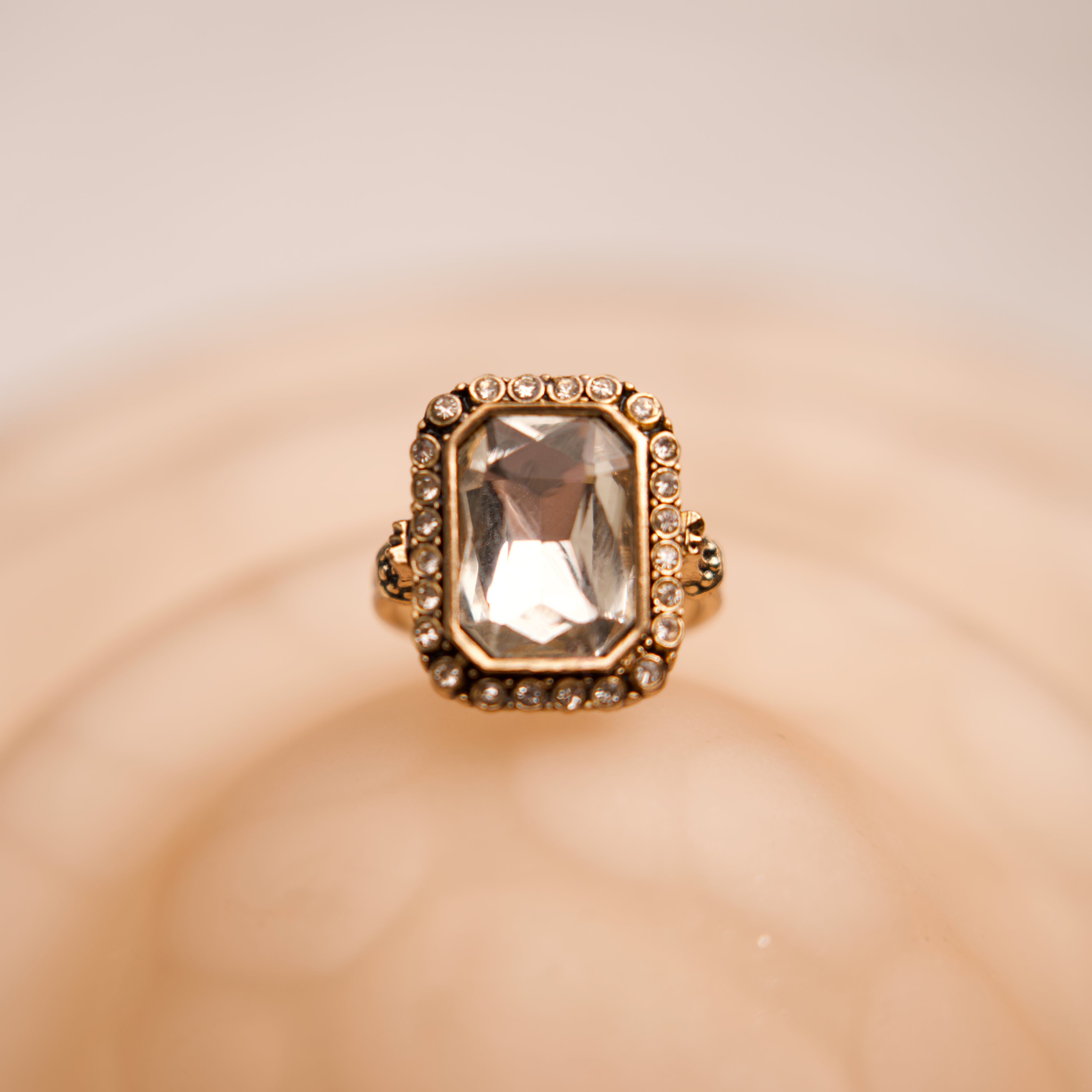 Gold ring with a large gemstone on a beige background