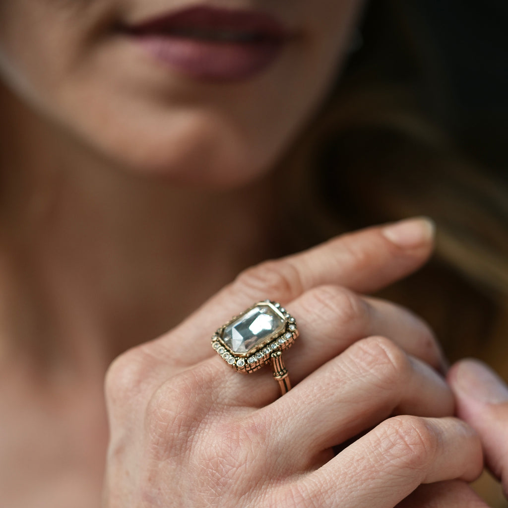 Close-up of a hand wearing an ornate ring with a large gemstone.