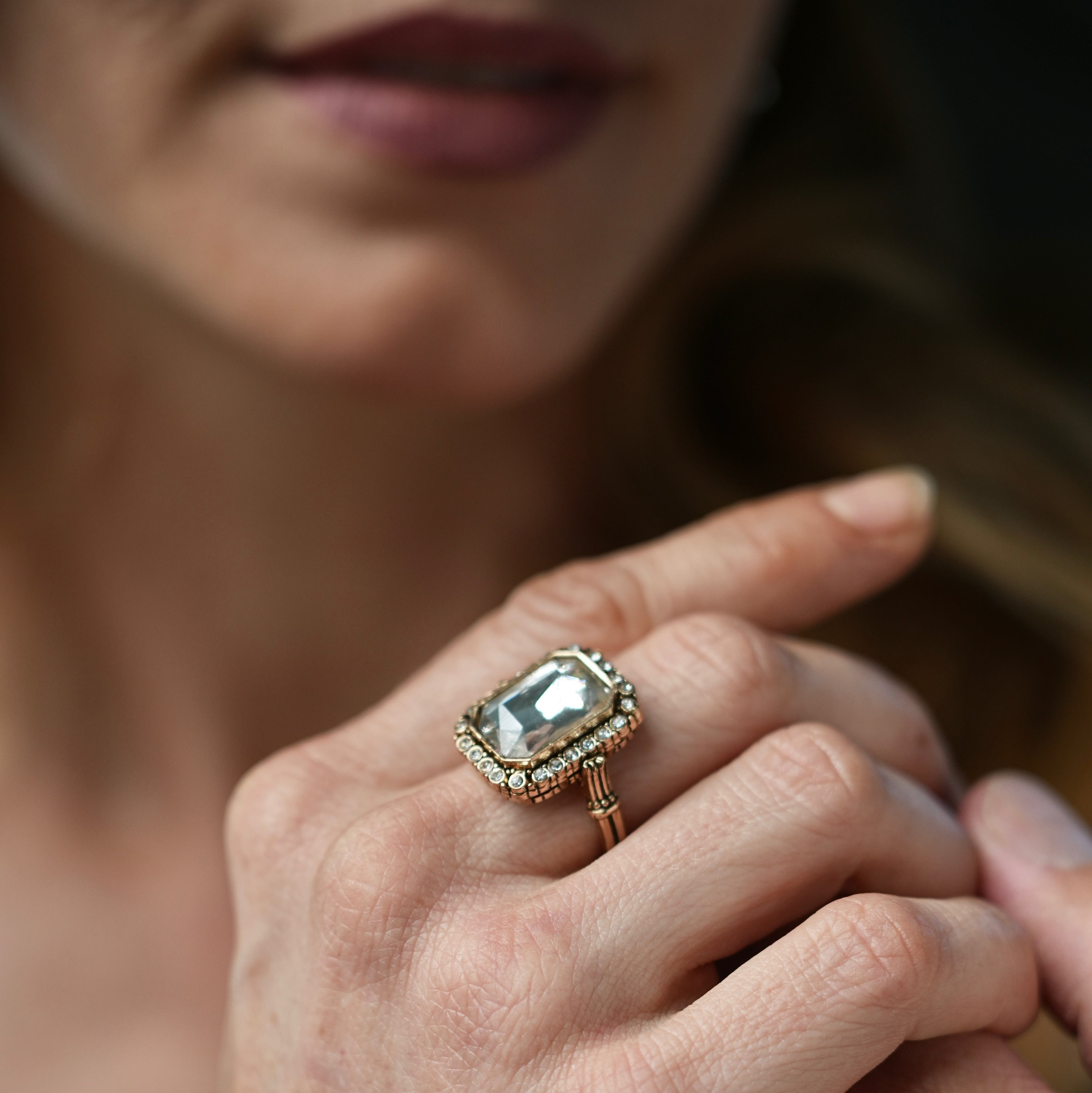Close-up of a hand wearing an ornate ring with a large gemstone.