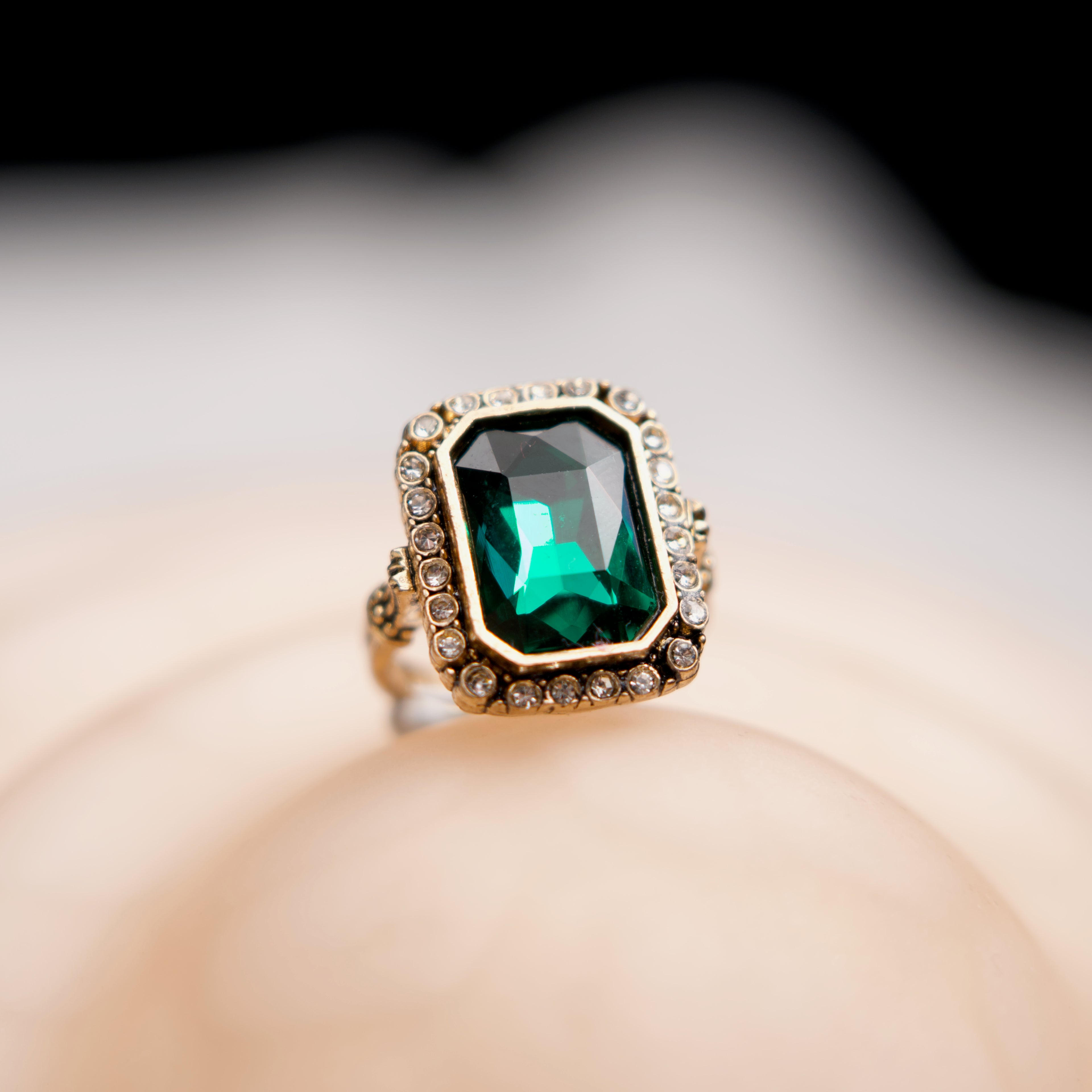 Gold ring with a green gemstone on a neutral background