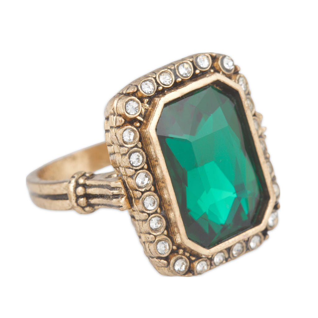 Gold ring with a green gemstone and diamond accents on a white background