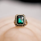 Ring with a green gemstone and gold accents on a soft beige background