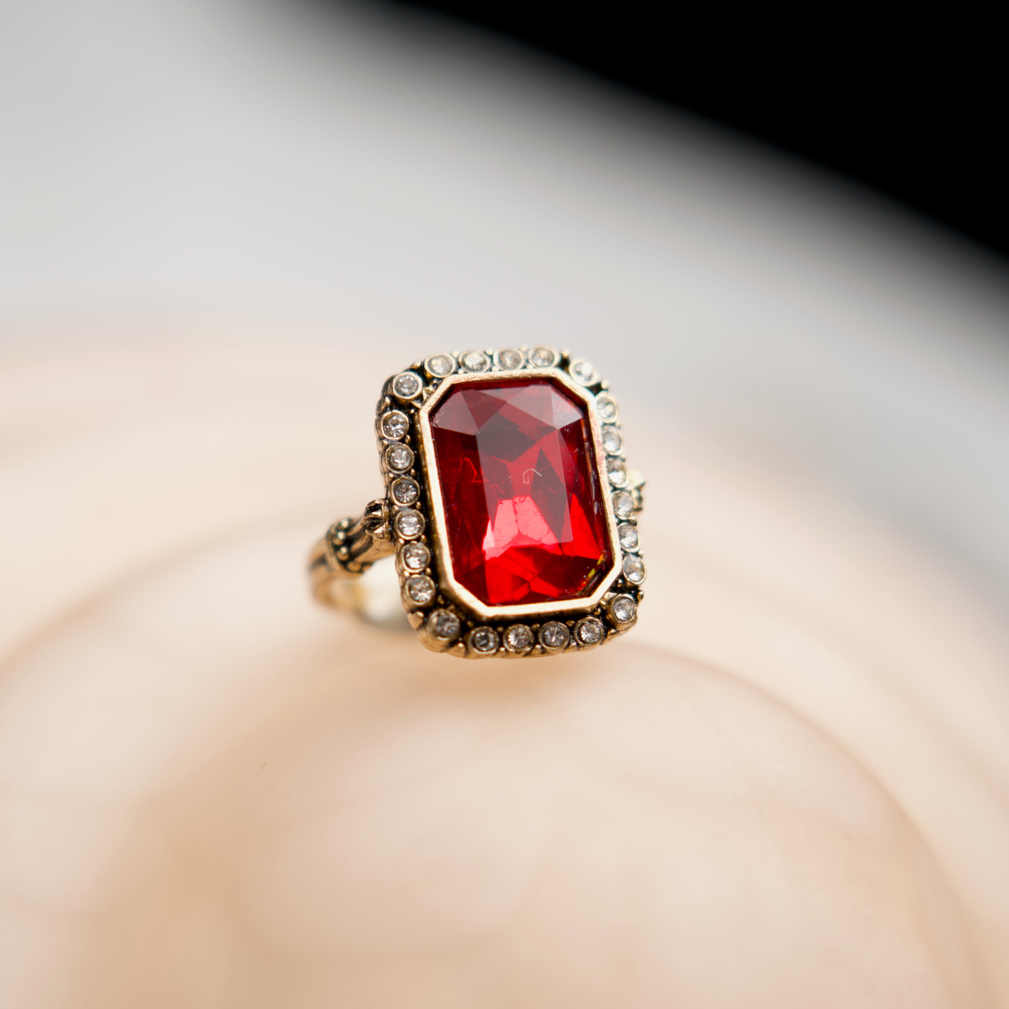 Gold ring with a red gemstone on a blurred background