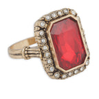 Ring with a red gemstone and gold-tone setting on a white background