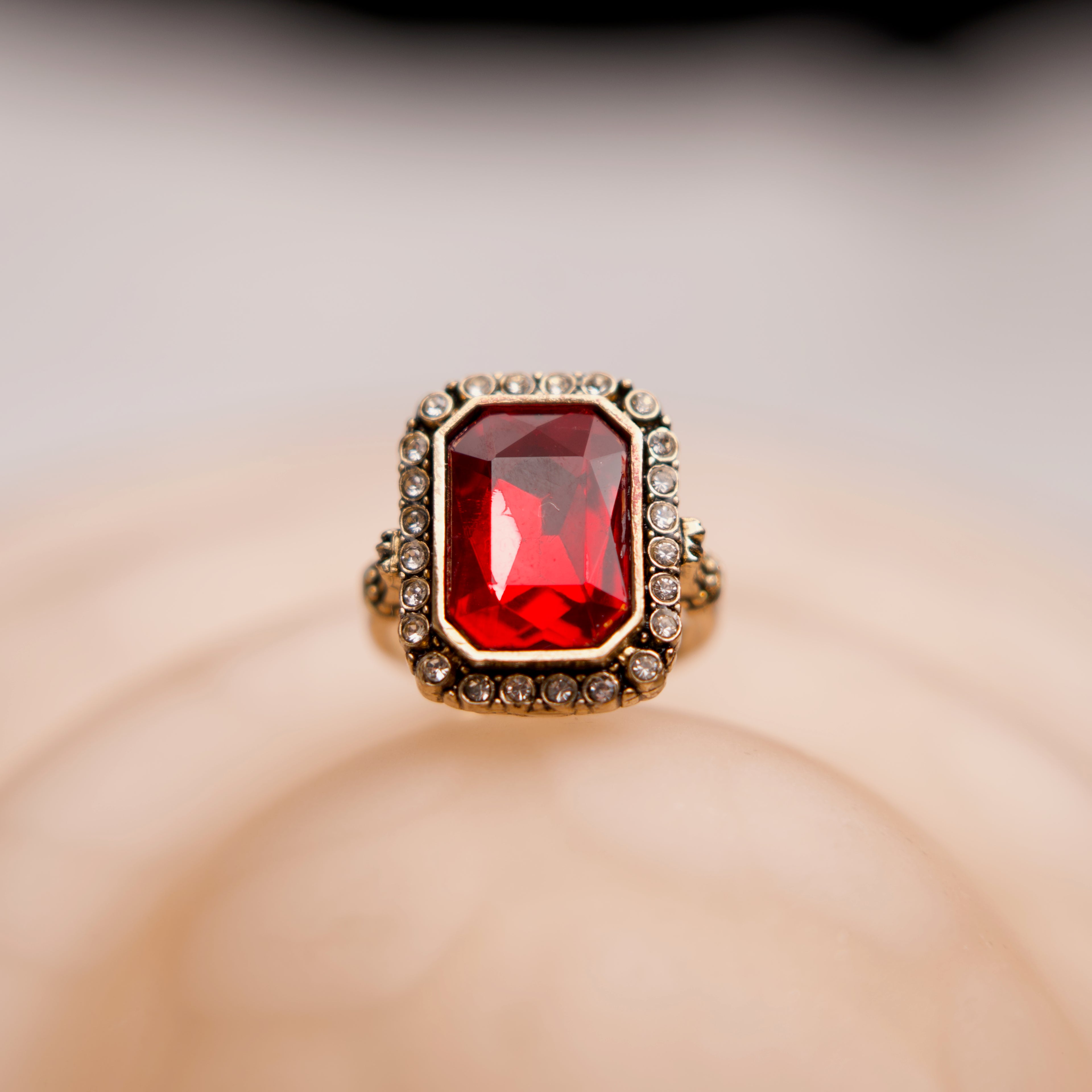Ring with a red gemstone and gold accents on a beige background