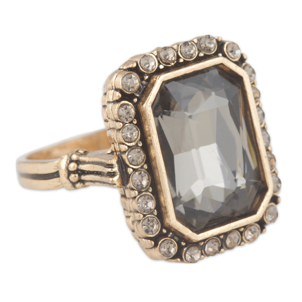 Gold ring with a large central gemstone and smaller stones on a white background
