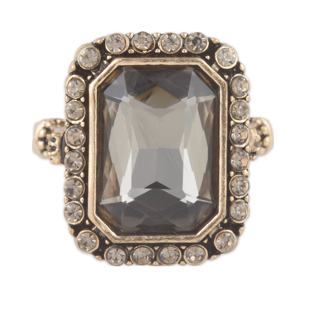 Ring with a large central gemstone and smaller stones around on a white background