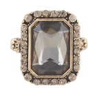 Ring with a large central gemstone and smaller stones around on a white background