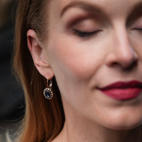Close-up of a woman wearing an earring with a dark gemstone against a blurred background