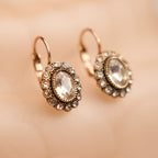 Pair of ornate earrings with gemstones on a beige background