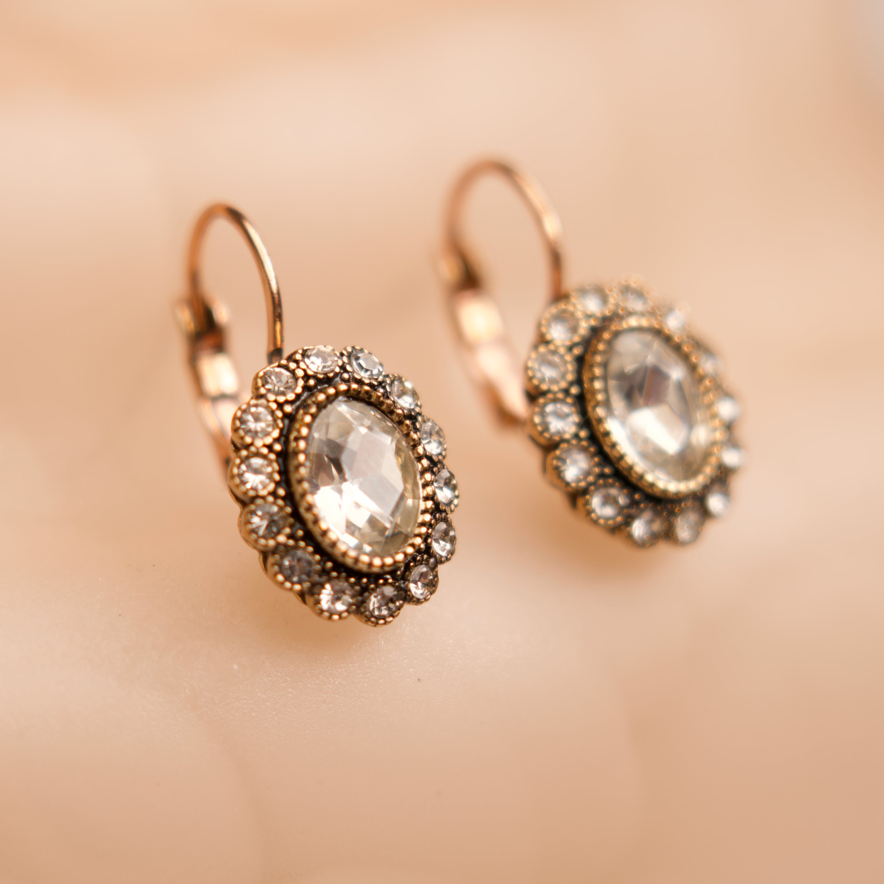 Pair of ornate earrings with gemstones on a beige background