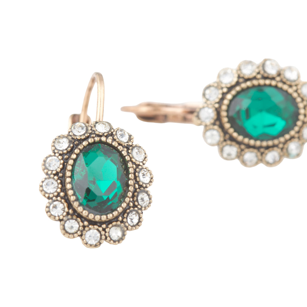 Gold earrings with green gemstones on a white background