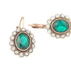 Gold earrings with green gemstones on a white background