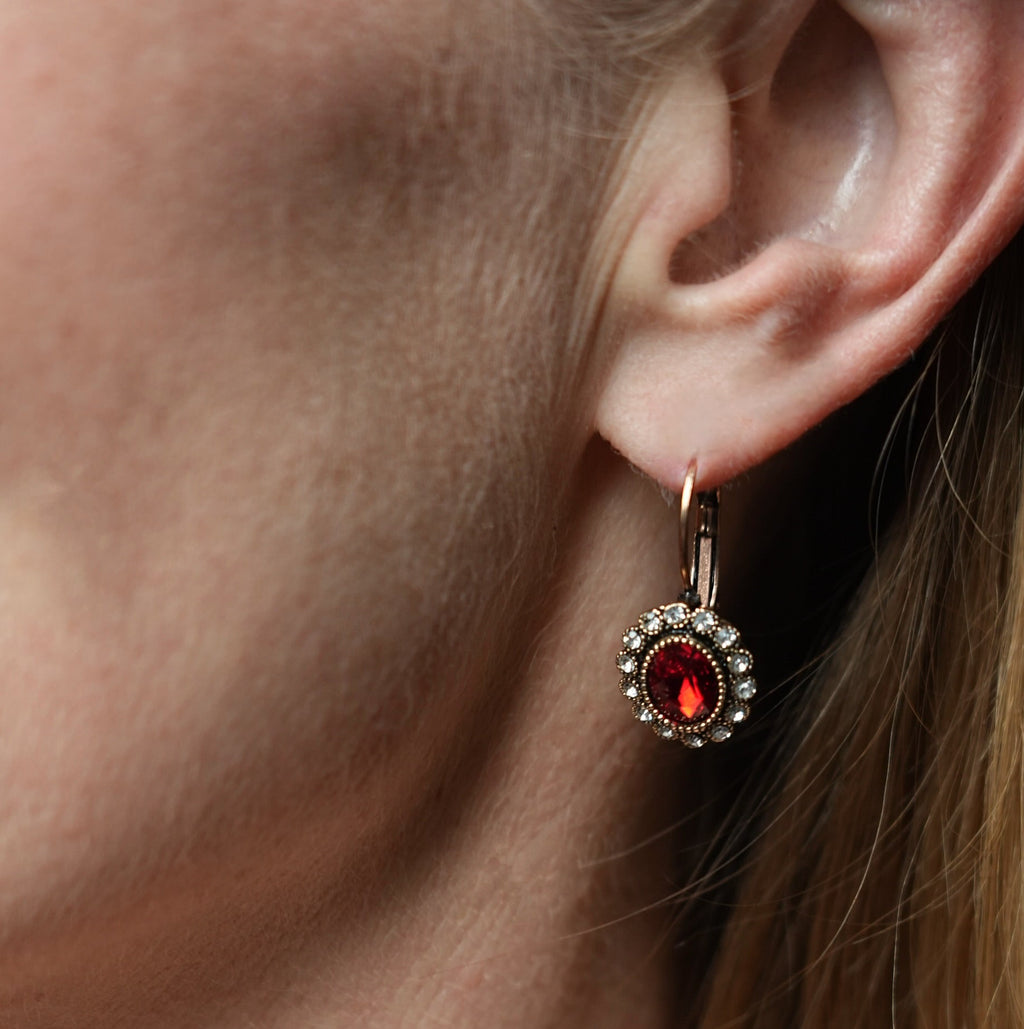 Close-up of an earring with a red gemstone on a person's ear.