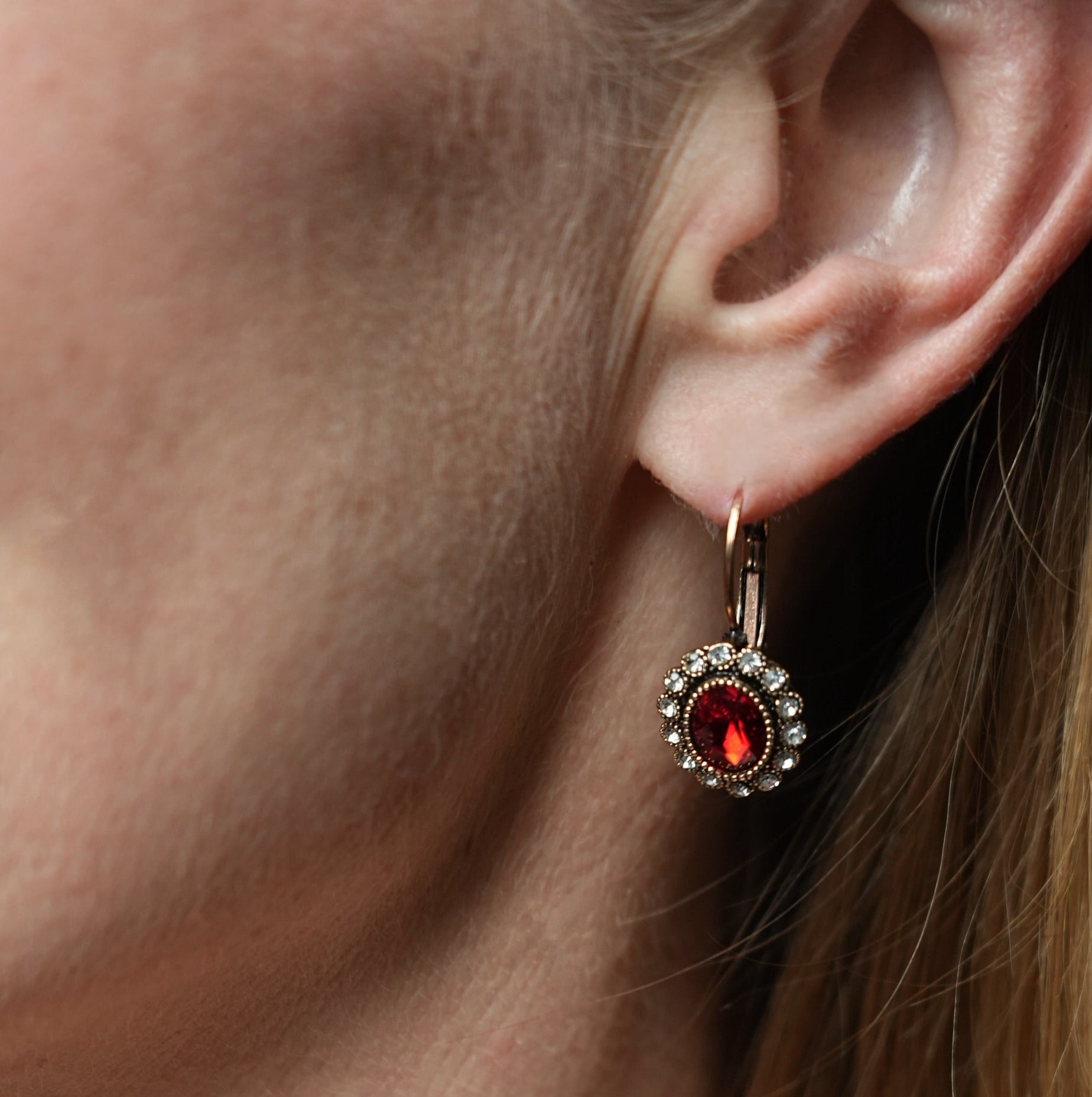 Close-up of an earring with a red gemstone on a person's ear.