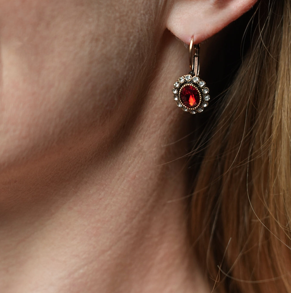 Close-up of an earring with a red gemstone on a person's ear.