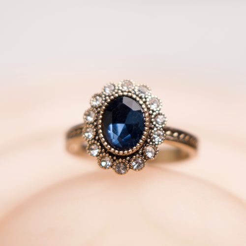 Ring with a blue gemstone and decorative band on a soft background