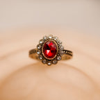 Gold ring with a red gemstone on a beige background