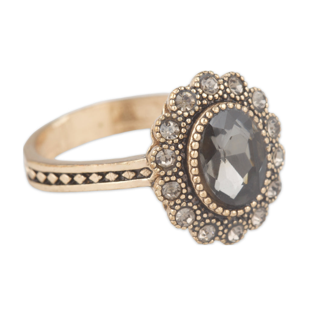 Gold ring with a dark gemstone and smaller stones on a white background