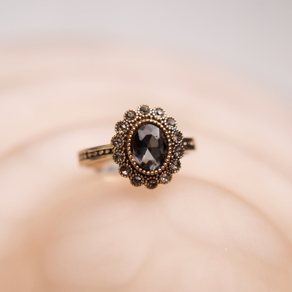 Gold ring with a black gemstone on a beige background
