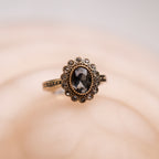 Gold ring with a black gemstone on a beige background