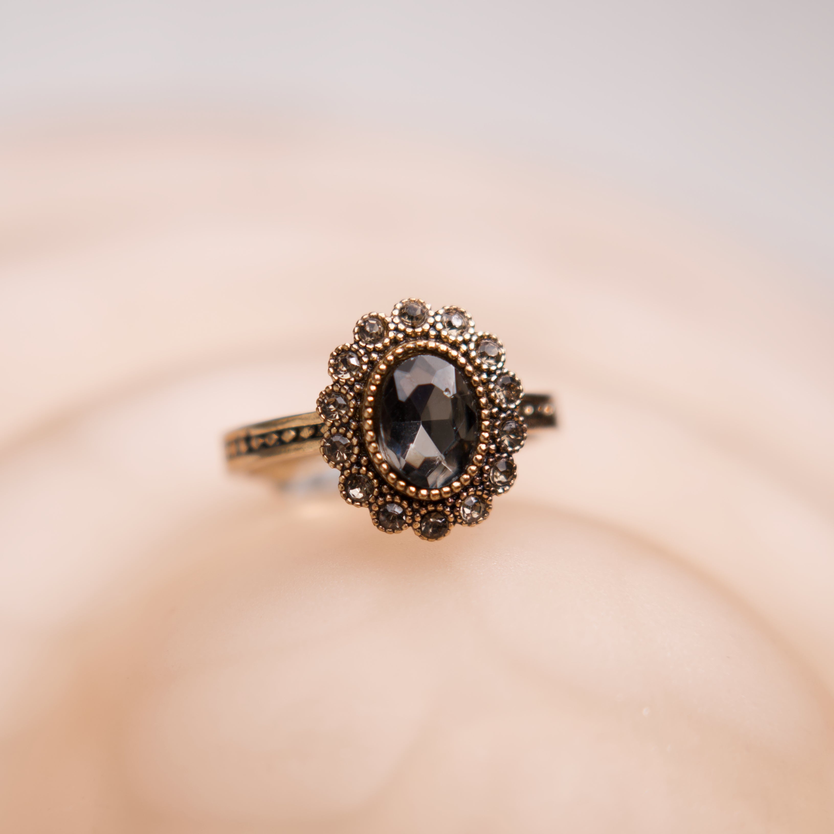 Gold ring with a black gemstone on a beige background