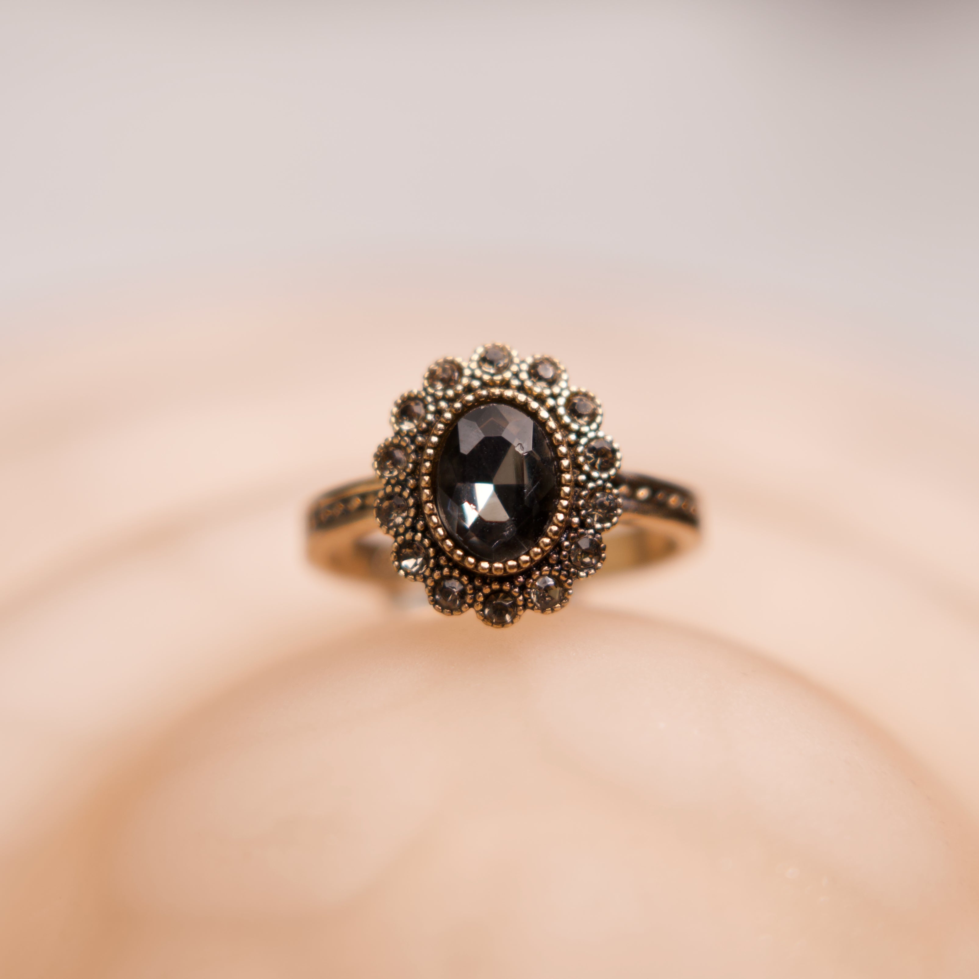 Gold ring with a black gemstone on a beige background
