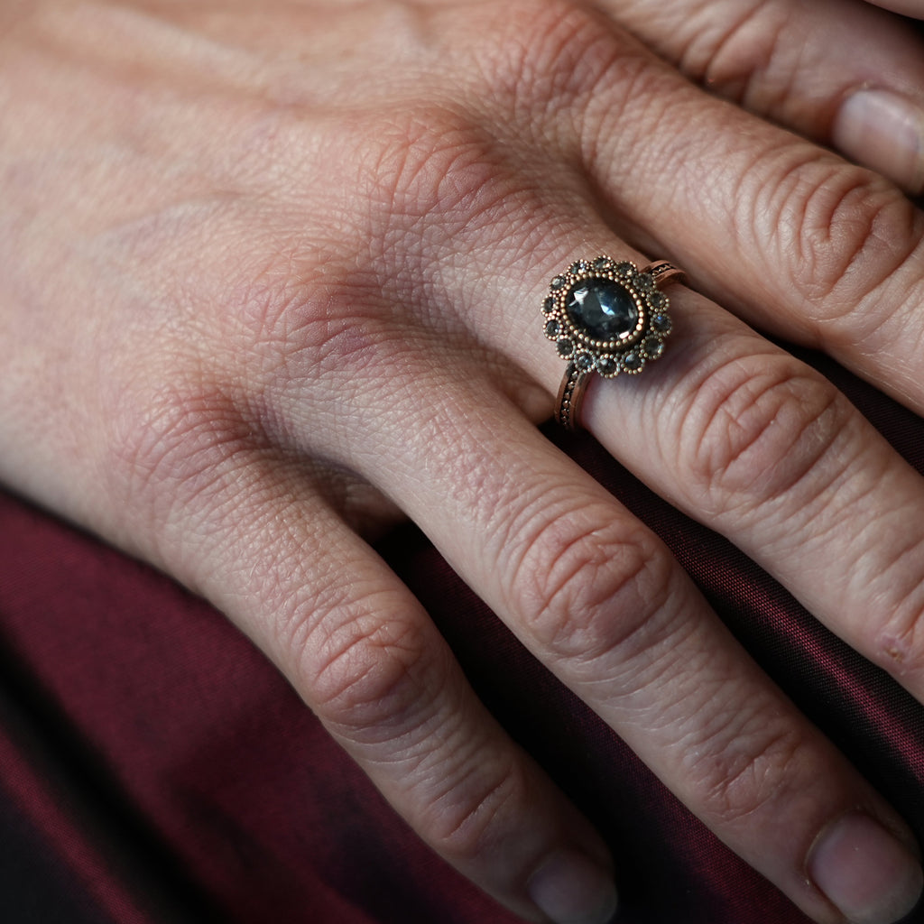 Close-up of a hand wearing a decorative ring with a dark gemstone.