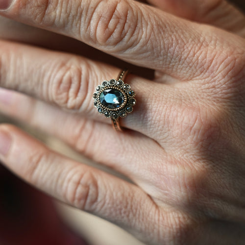 Close-up of a hand wearing a ring with a blue gemstone.
