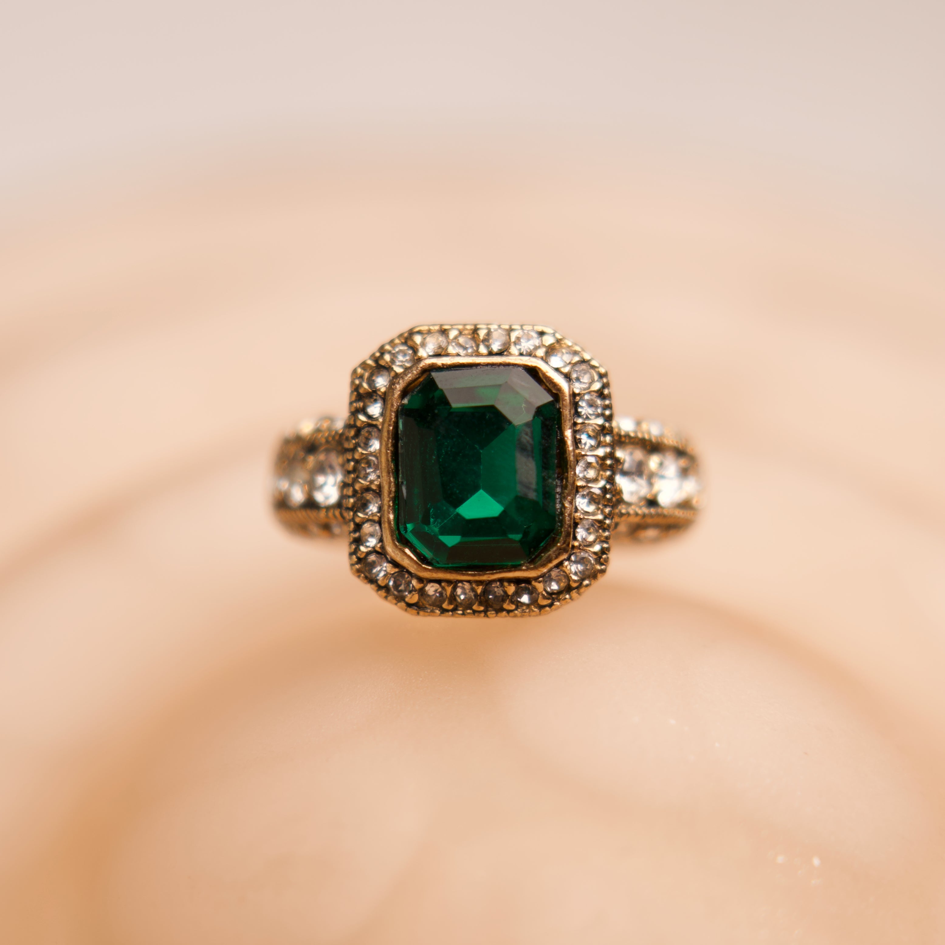 Ring with a green gemstone and gold accents on a blurred background