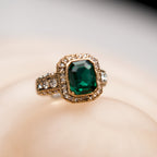 Gold ring with a green gemstone on a beige background