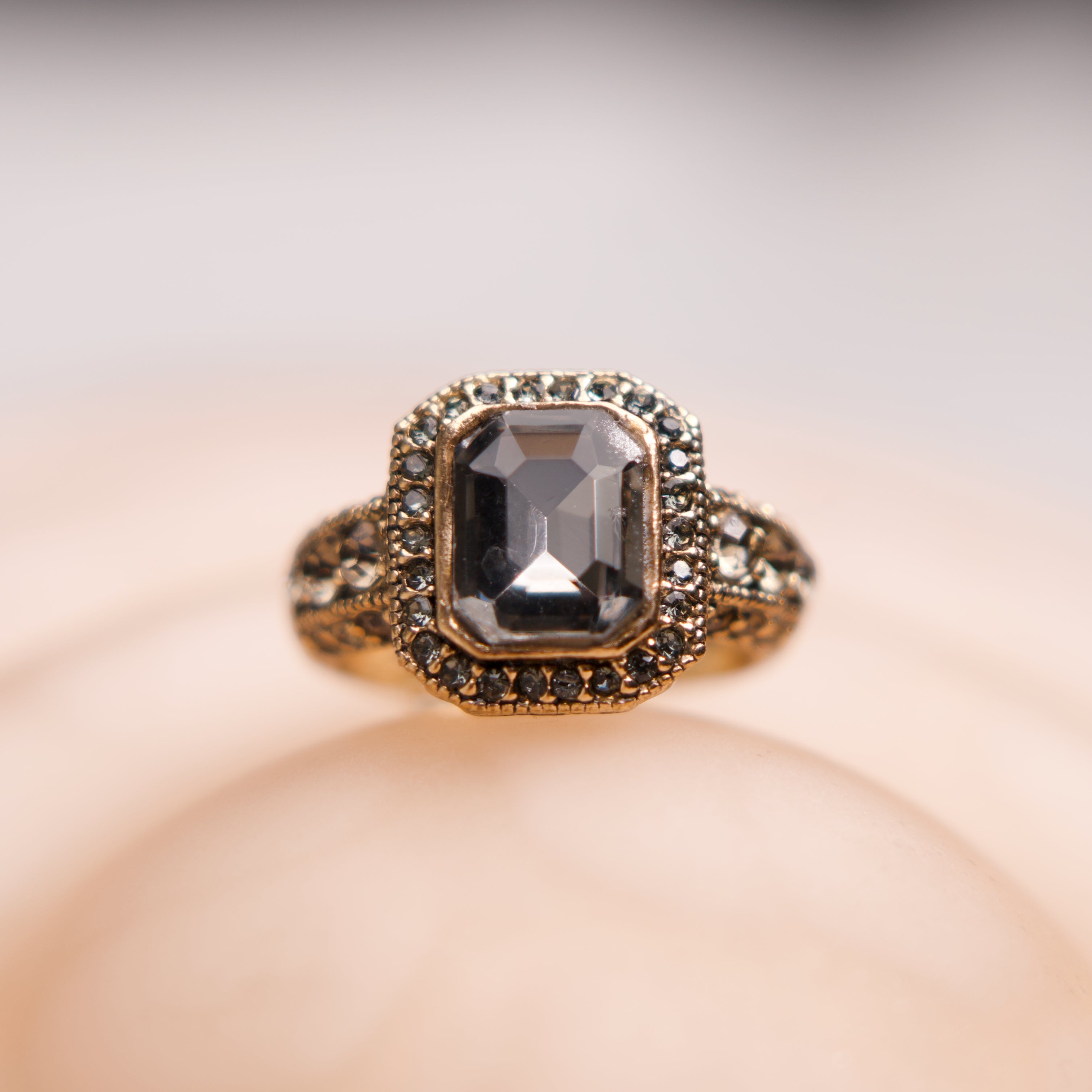 Gold ring with a central gemstone on a soft beige background