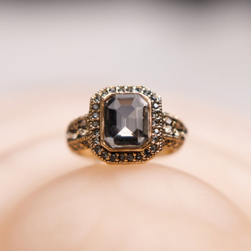 Gold ring with a central gemstone on a soft beige background
