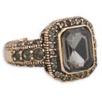 Decorative ring with a large black gemstone and smaller green stones on a white background