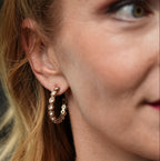 Close-up of a woman wearing gold hoop earrings with a blurred background