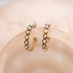Pair of pearl hoop earrings on a soft pink background