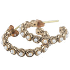 Pair of gold hoop earrings with pearl-like beads on a white background